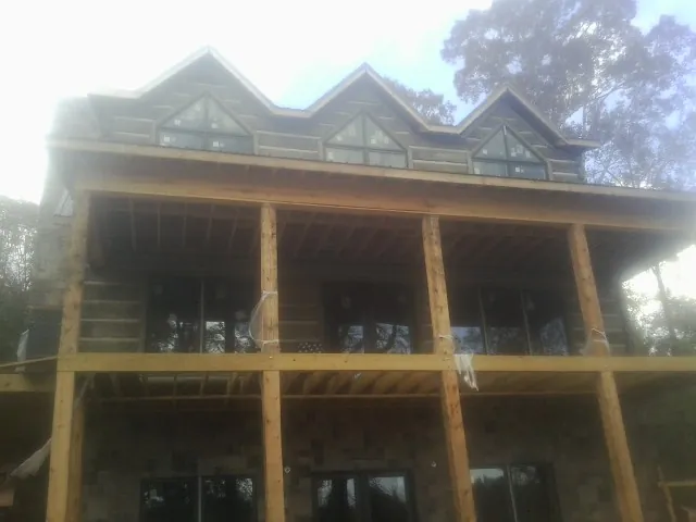 Dormers and porch framing on a large log home under construction — Roof Coating work by our crew in Pylesville