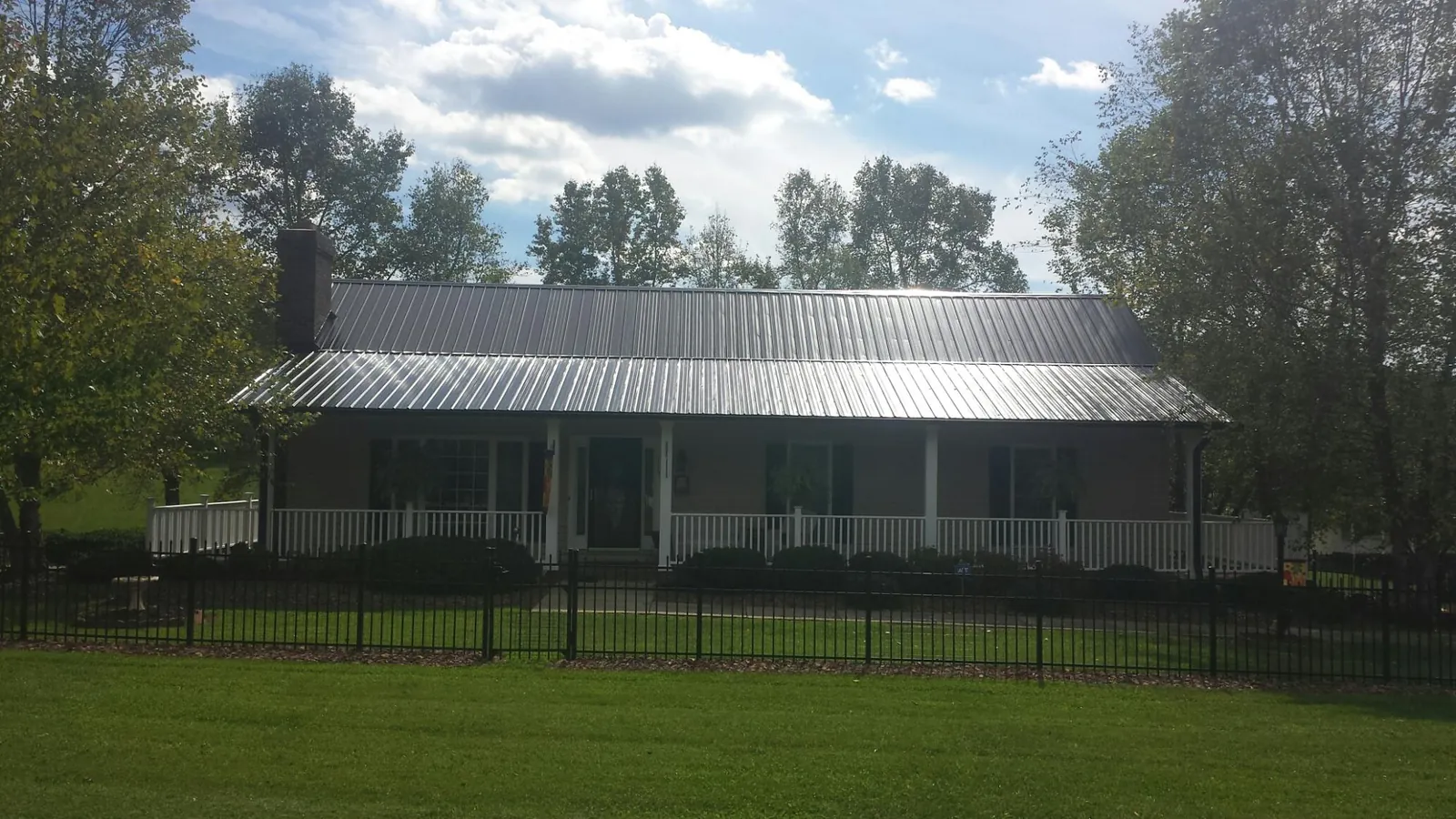 Gray metal roof on a brick ranch with a full width front porch — Gutter Guard Installation work by our crew in Pylesville
