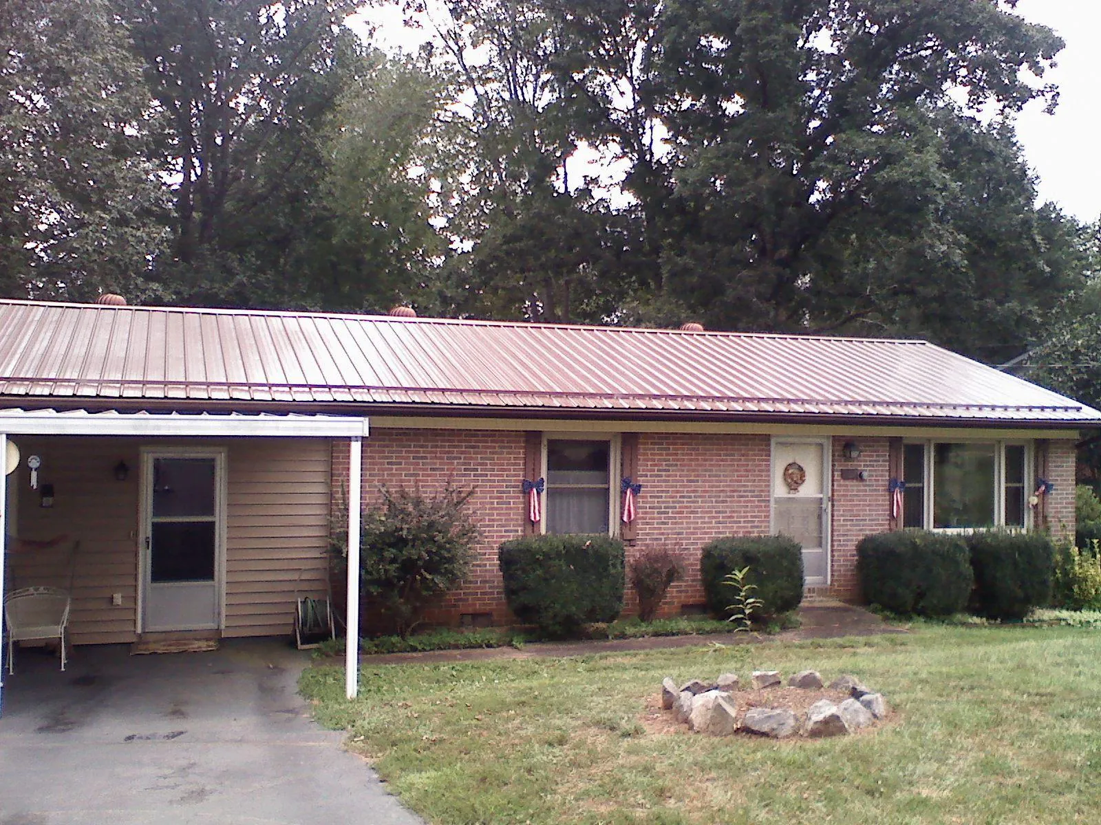Bronze metal roof and carport on a brick ranch home — Roof Repair work by our crew in Pylesville