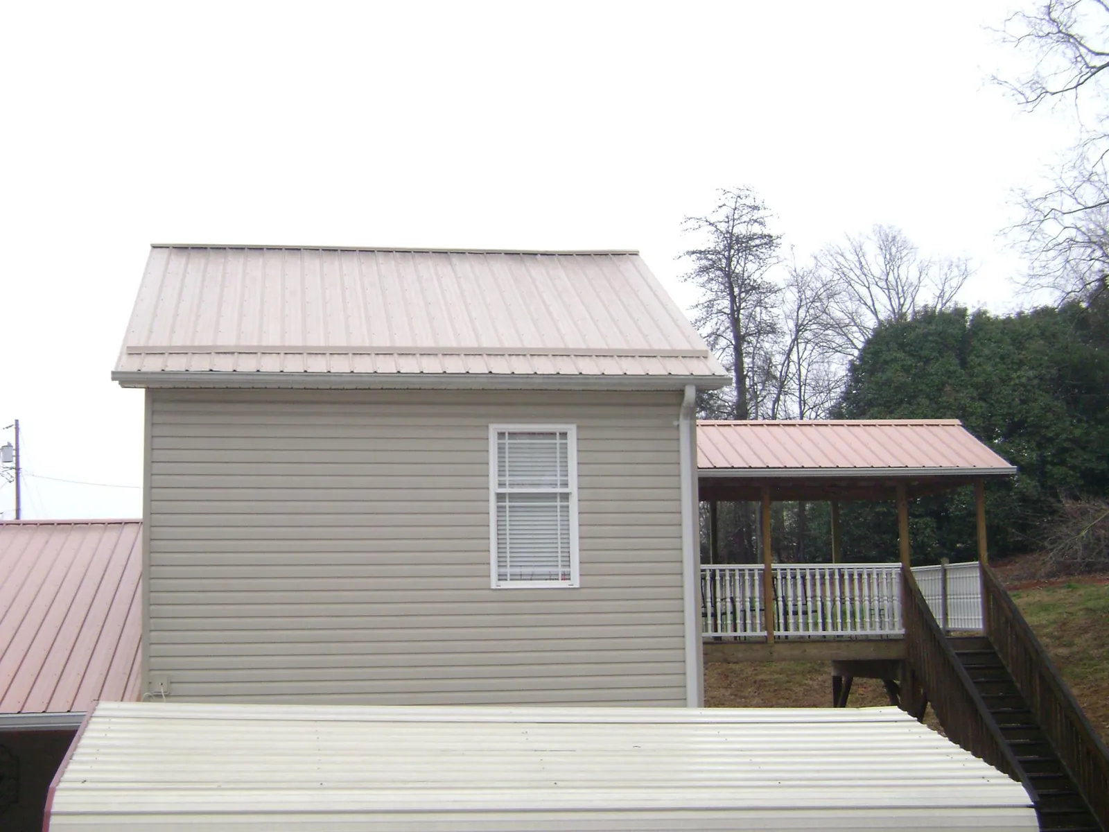 Tan metal roofs on a two story addition and attached porch, from a Roof Replacement job in Pylesville