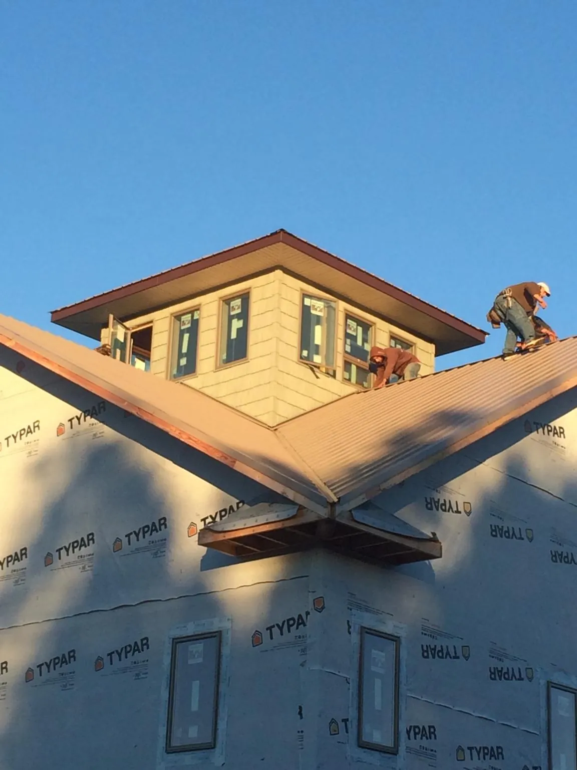 Roofers working around a rooftop cupola on a new metal roof at sunset — Roof Waterproofing in Pylesville by Roofing Brothers